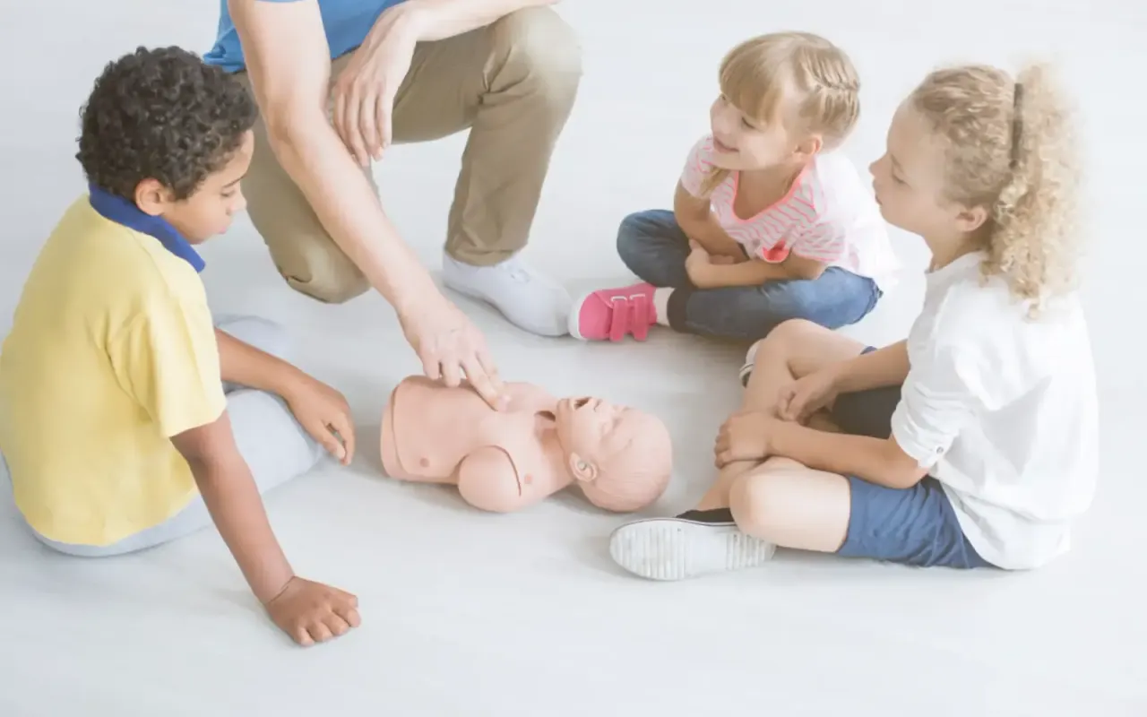 Kinderen kijken naar een reanimatie-oefening op een babypop