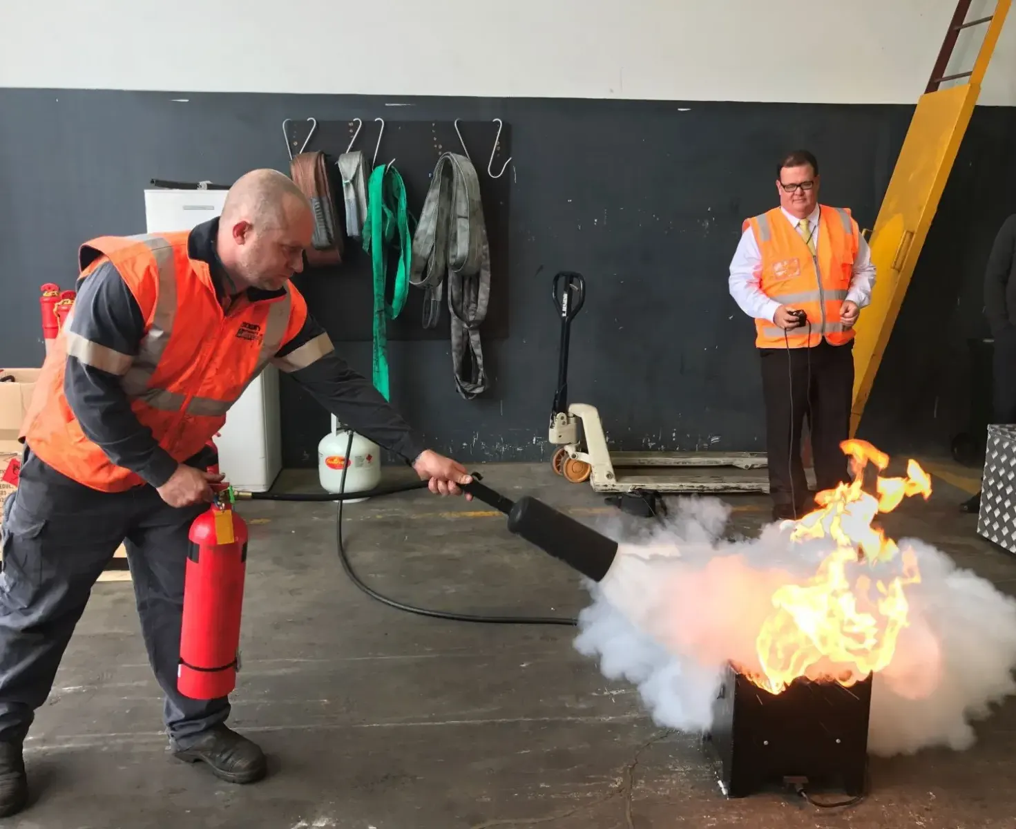 Deelnemers oefenen brandbestrijding met een blusser tijdens een BHV-training